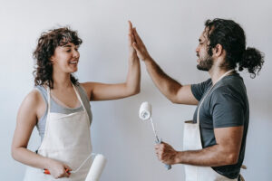 couple doing a home renovation do a high 5 with paint rollers